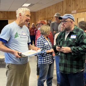 With clipboard in hand, Paul talks with Martin at the spring potluck, in front of line for the buffet